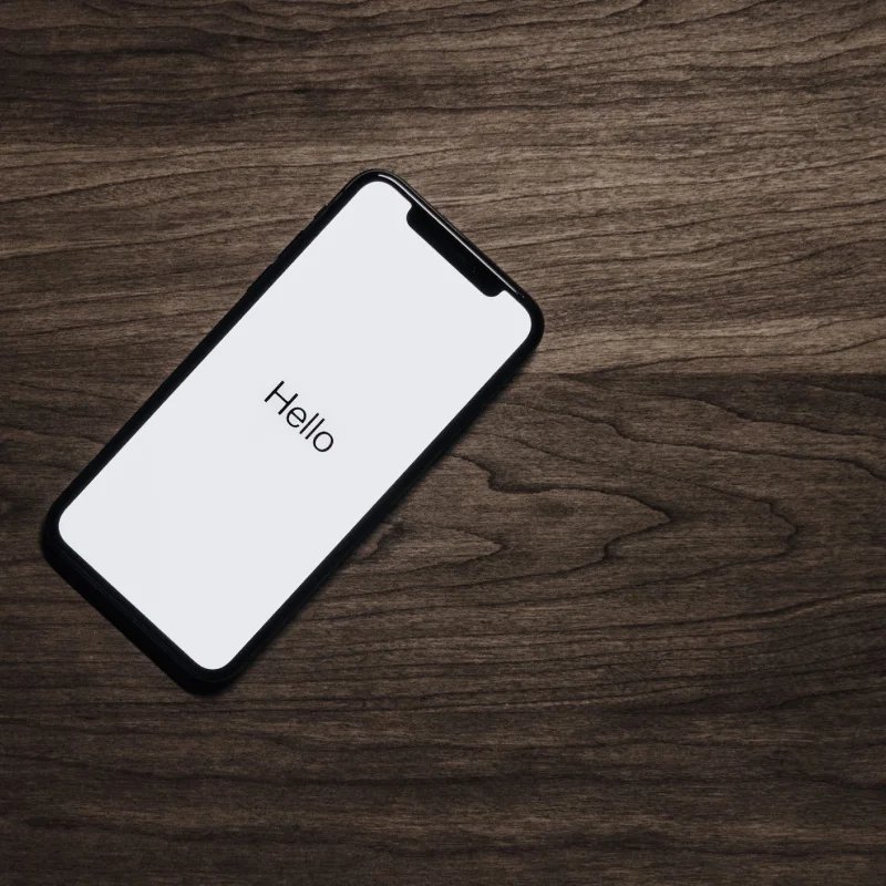 Mobile phone on a hardwood floor with a screen that reads Hello
